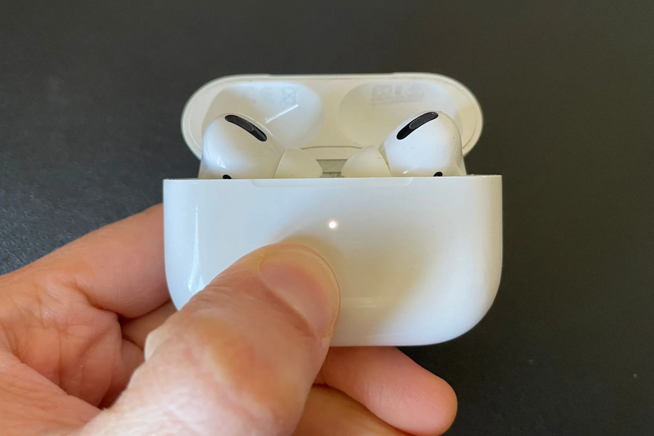 AirPods Pro bên trong hộp sạc với đèn trạng thái màu trắng, minh họa thiết kế tích hợp pin không thể thay thế