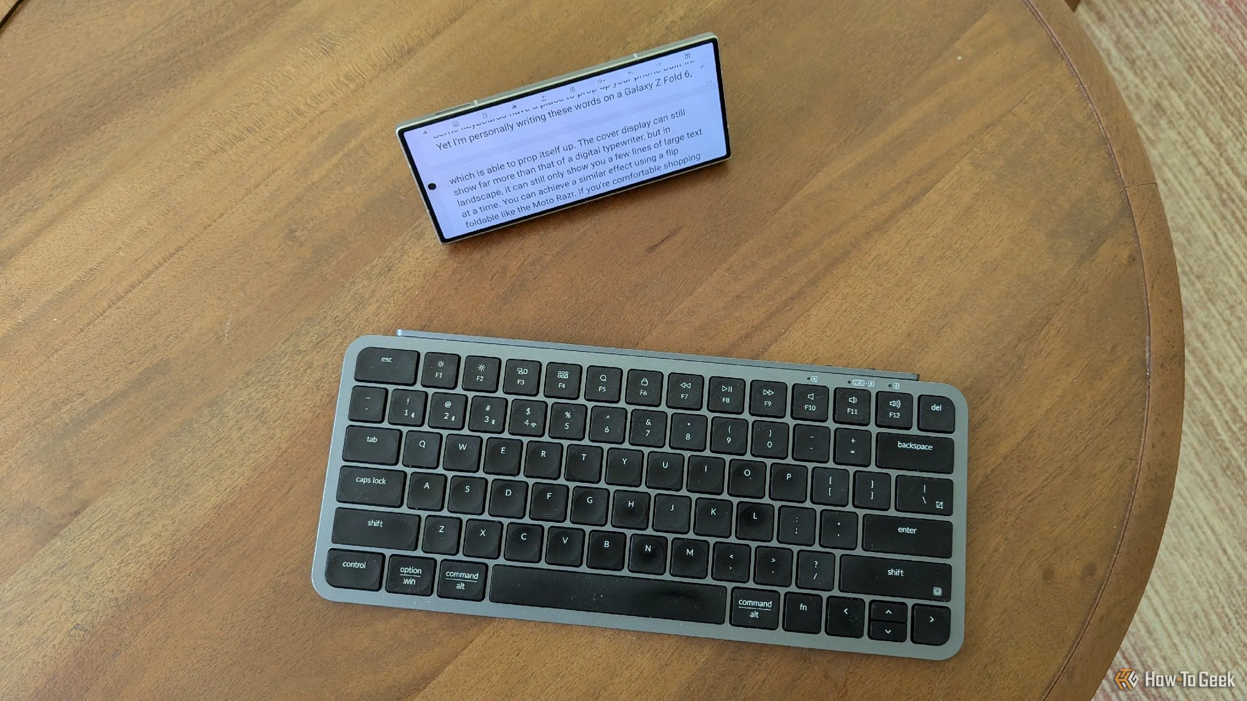Bàn phím Bluetooth kết nối với điện thoại Galaxy Z Fold 6 đang đặt trên chân đế.