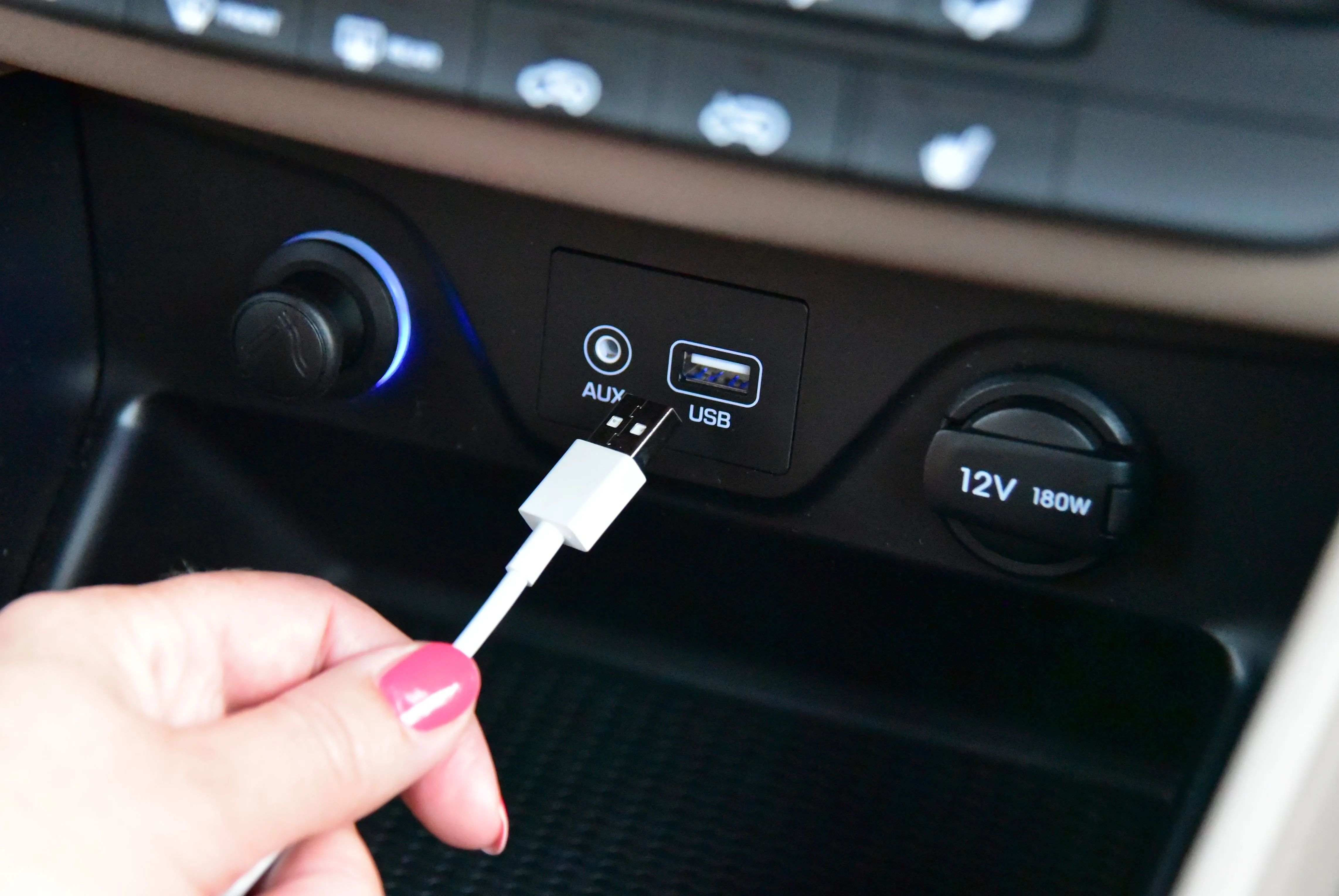 Bàn tay đang cố gắng cắm cáp USB-A vào cổng sạc trên ô tô, minh họa thói quen lật đầu cáp