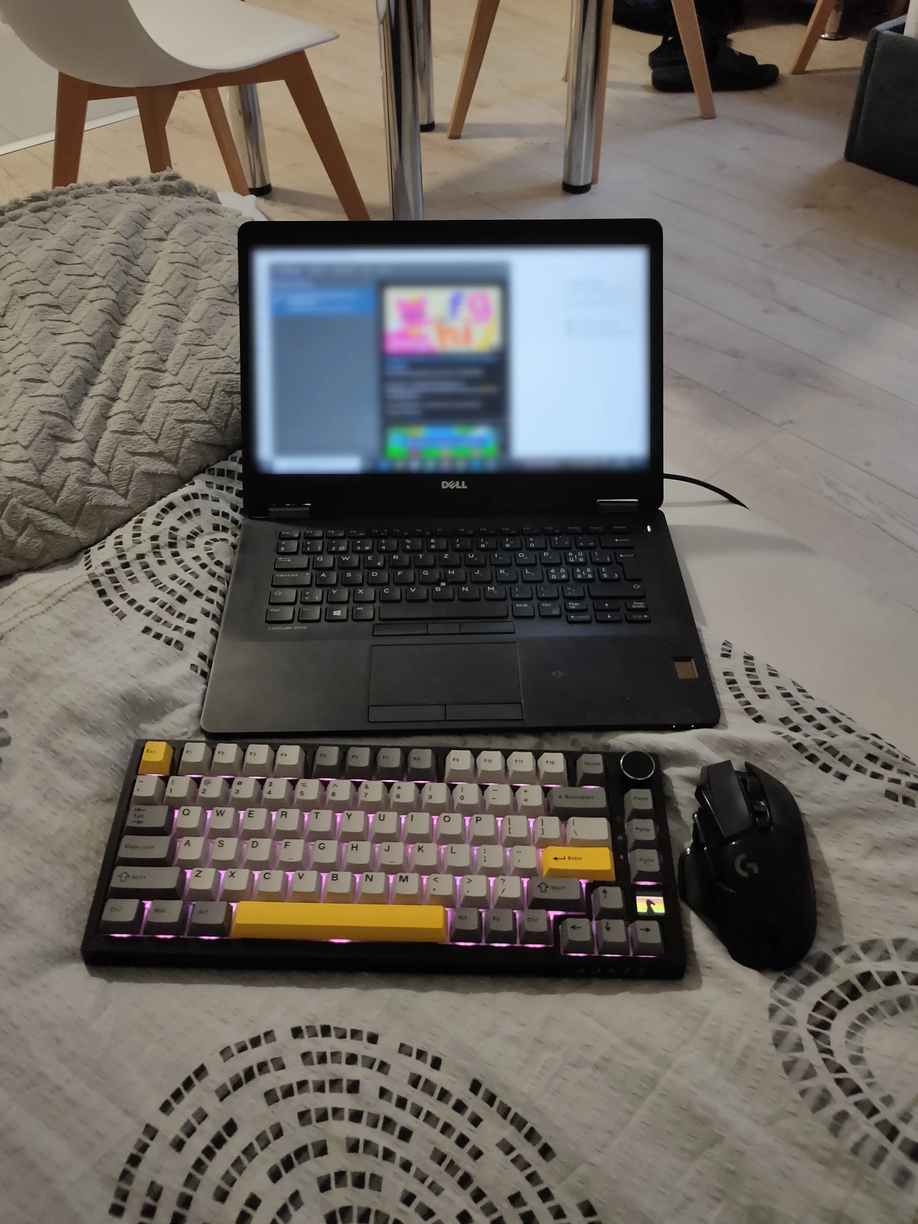 Bộ bàn phím và chuột không dây đặt cạnh laptop trên giường, tạo không gian chơi game thoải mái và linh hoạt