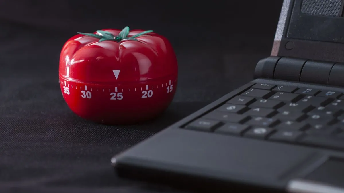 Bộ hẹn giờ Pomodoro cổ điển đặt cạnh laptop, minh họa phương pháp quản lý thời gian hiệu quả.