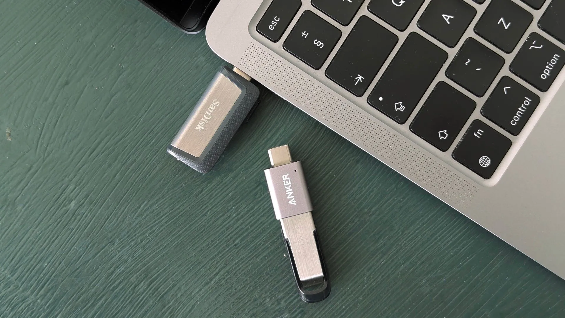 Các loại USB flash drive khác nhau đặt cạnh MacBook, minh họa sự đa dạng về cổng kết nối và kích thước