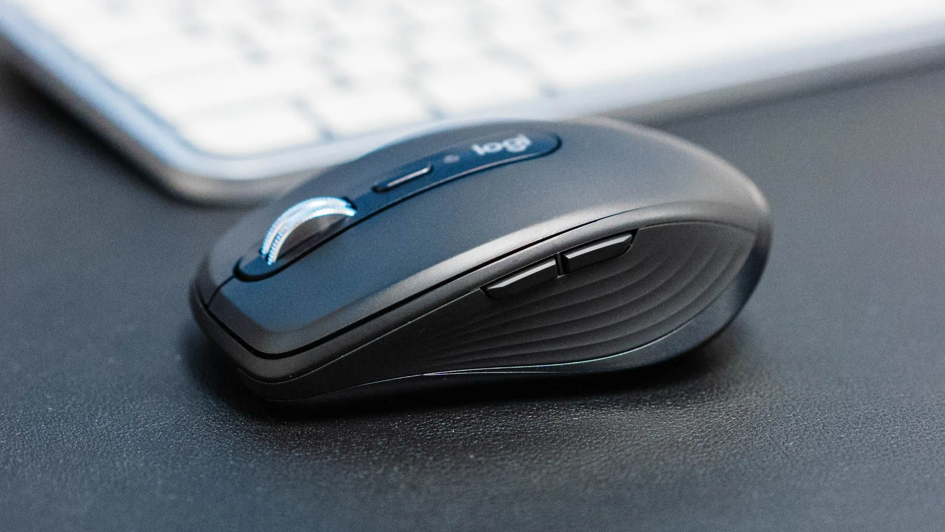 Chuột Logitech MX Anywhere 3S đặt nghiêng trước bàn phím, thể hiện sự nhỏ gọn và tiện lợi cho không gian làm việc di động