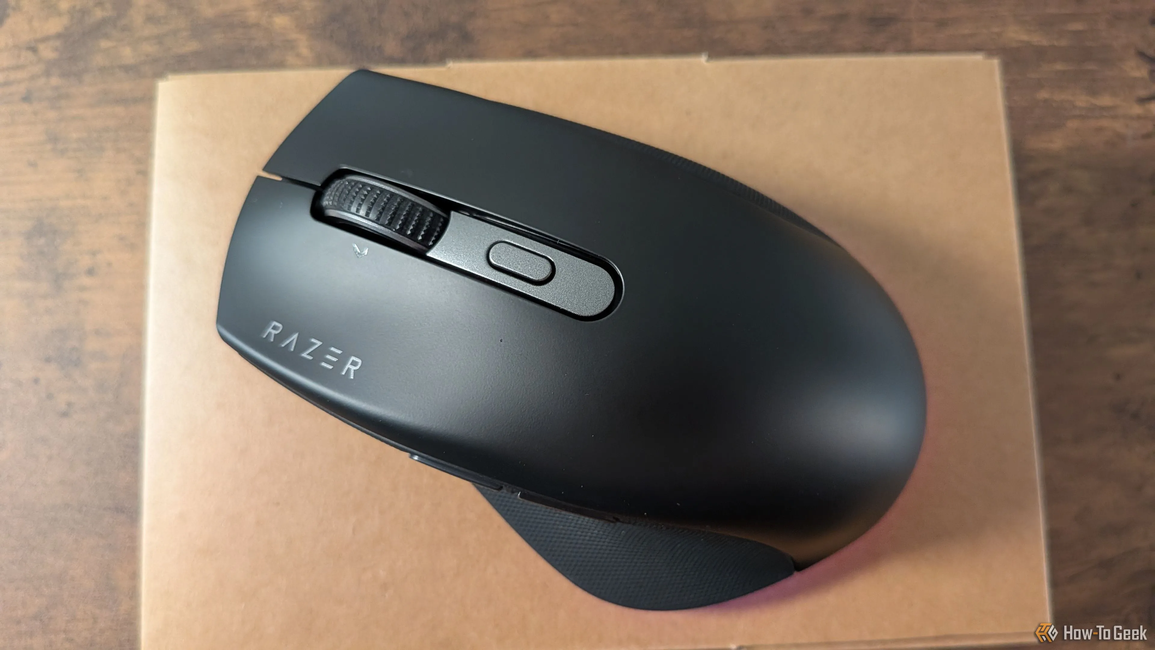 Chuột Razer Pro Click V2 đặt trên hộp, với dải đèn LED dưới thân chuột đang sáng, thể hiện thiết kế tinh tế