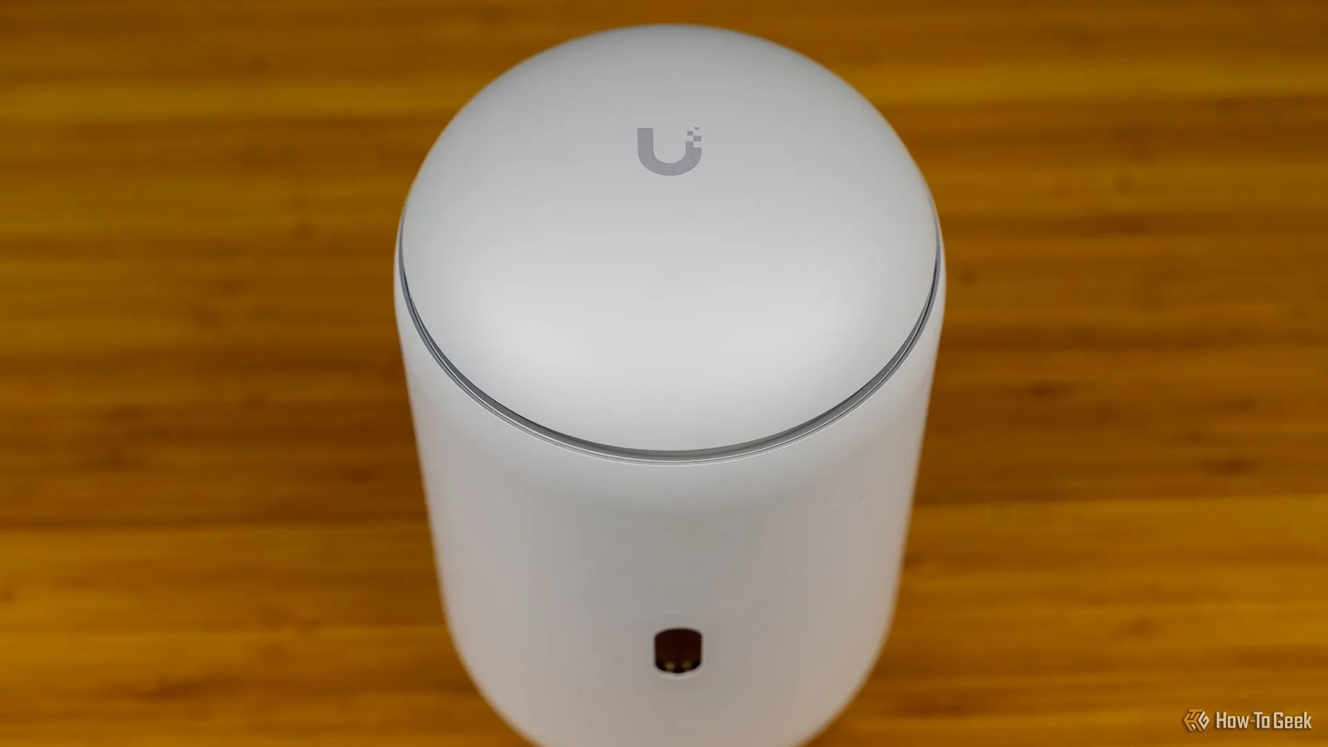 Hình ảnh nhìn từ trên xuống của Unifi Dream Router 7, làm nổi bật logo Unifi trên đỉnh thiết bị