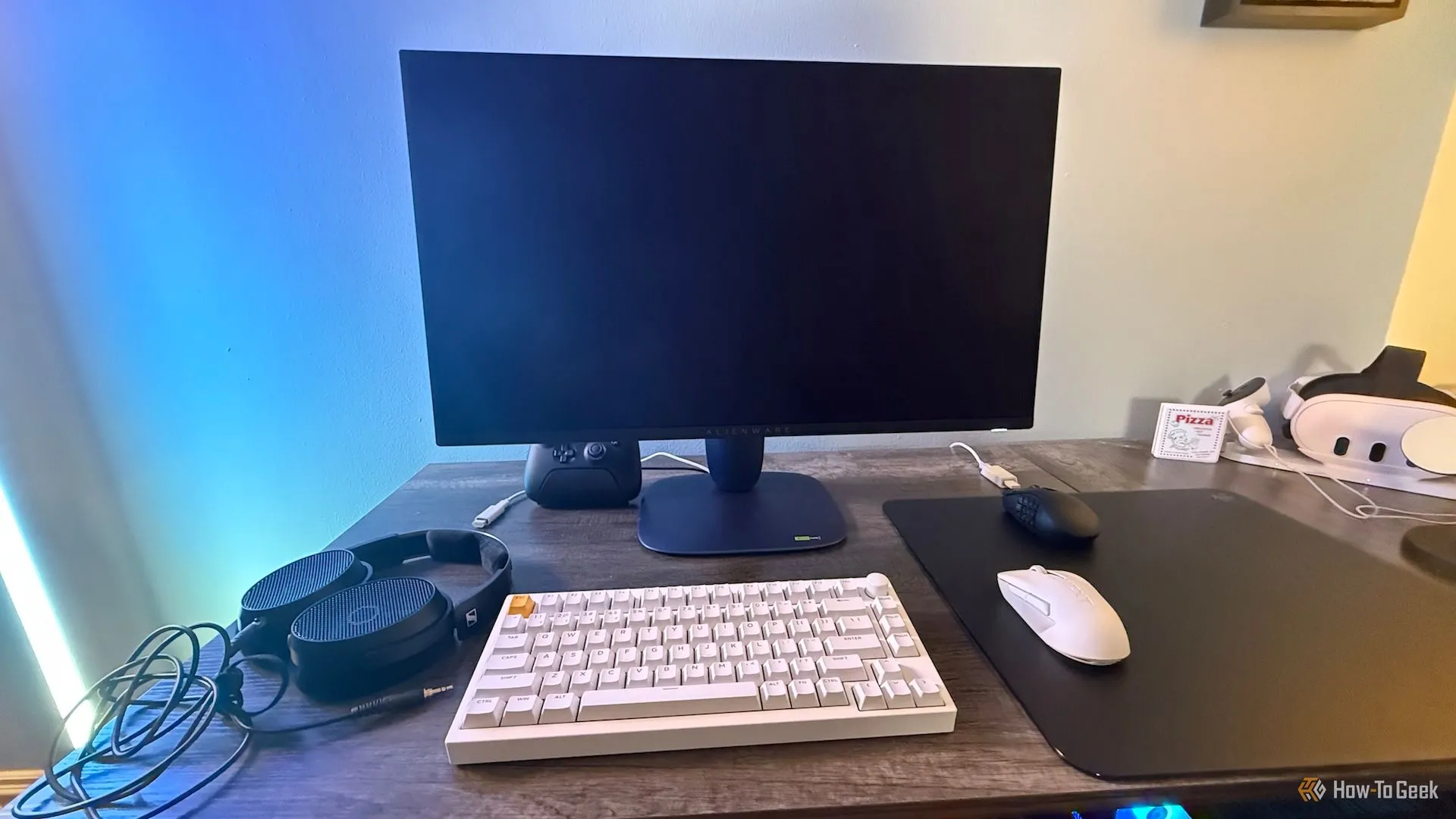Màn hình Alienware 27 4K QD-OLED (AW2725Q) trên bàn làm việc cùng các thiết bị PC và gaming khác.