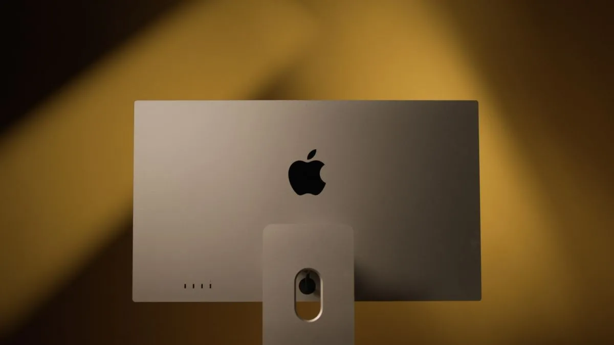 Mặt sau của màn hình Apple Studio Display với chân đế kim loại, đặt trên nền vàng, nhấn mạnh chất lượng hiển thị cao cấp cho Mac