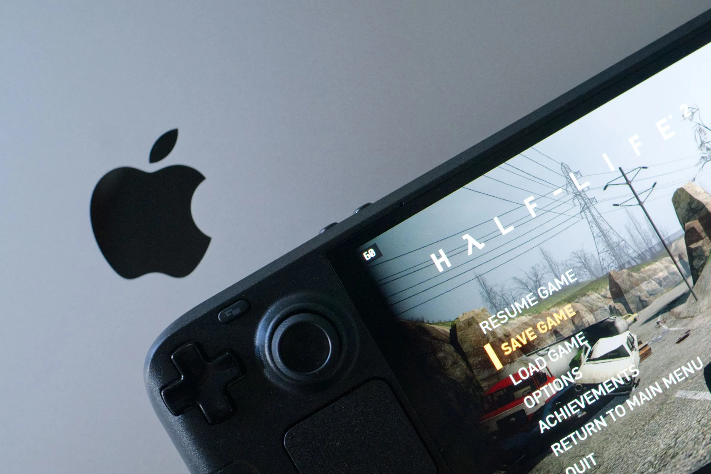 Máy chơi game cầm tay Steam Deck OLED đang chạy Half-Life 2 đặt trên bàn phím MacBook Pro, thể hiện sự đa dạng của trải nghiệm chơi game PC