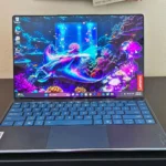 Máy tính xách tay Lenovo Yoga Slim 9i Gen 10 màu bạc sang trọng đặt trên bàn, minh họa sự đa dạng của các dòng laptop hiện nay.