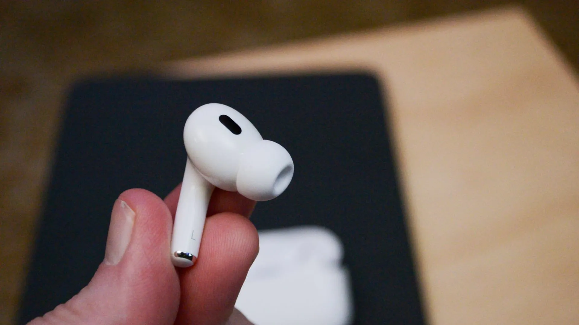 Một chiếc tai nghe Apple AirPods Pro thế hệ 2 màu trắng đặt trên bề mặt màu tối, biểu tượng cho giải pháp âm thanh cá nhân và sự tiện lợi của tai nghe không dây hiện đại.