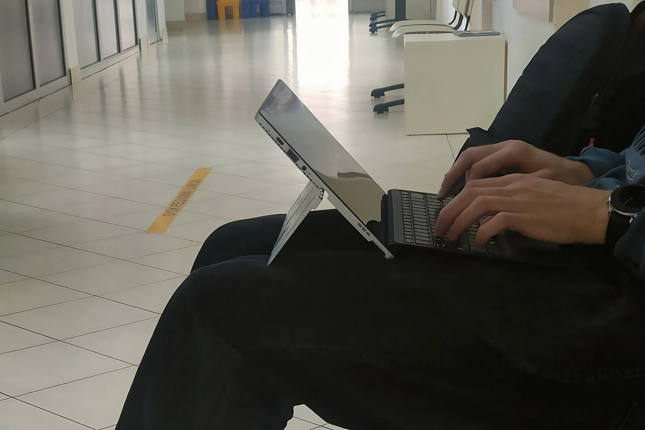 Người dùng gõ phím trên laptop 2 trong 1 đặt trên đùi, so sánh với trải nghiệm dùng bàn phím rời.