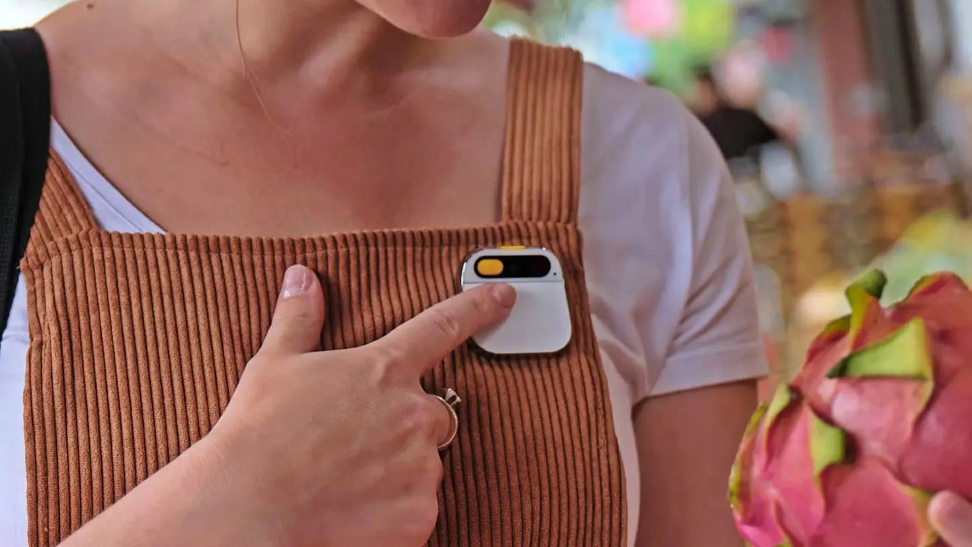 Người phụ nữ đeo Humane AI Pin trên ve áo đang tương tác với thiết bị bằng cử chỉ tay