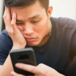 Người phụ nữ tập trung cuộn điện thoại trên ghế chờ sân bay, thể hiện sự mất kết nối với môi trường xung quanh và hiện tượng doomscrolling.