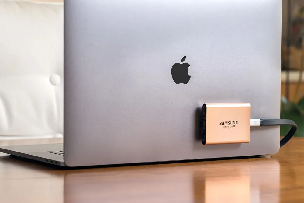 Ổ cứng SSD di động Samsung T5 được gắn vào MacBook Pro bằng băng dính Velcro, minh họa giải pháp lưu trữ tiện lợi.