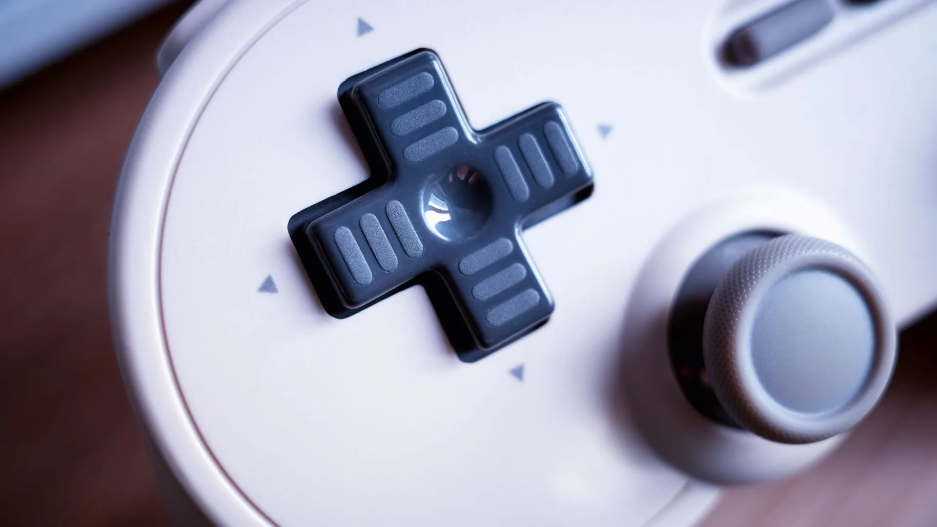 Tay cầm chơi game cổ điển với D-Pad, gợi nhớ cách điều khiển truyền thống của game platformer.