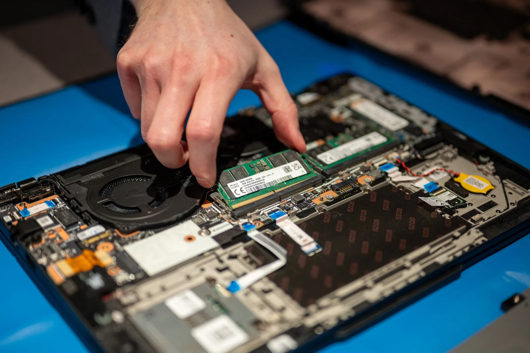 Thanh RAM được tháo rời từ laptop Lenovo cho thấy bo mạch chủ và các linh kiện khác, minh họa quá trình nâng cấp RAM laptop văn phòng