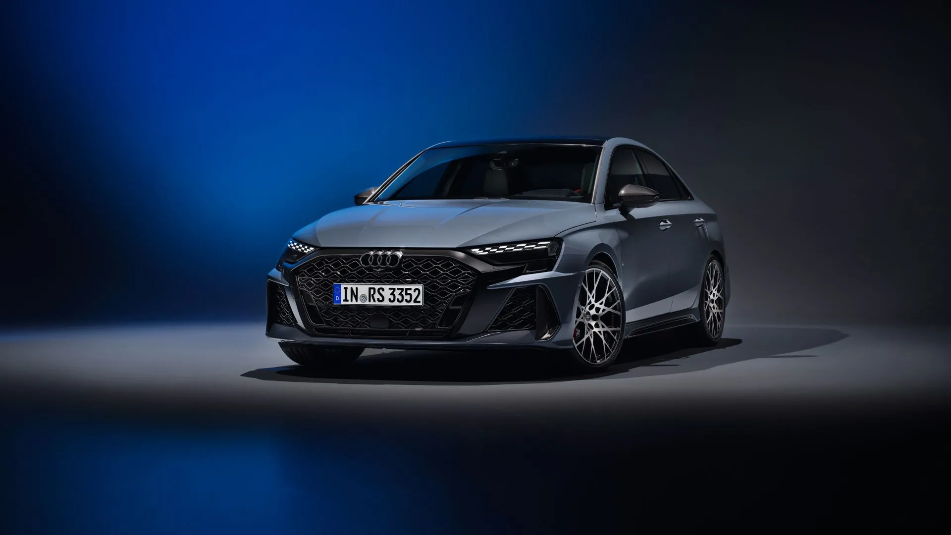Audi RS3 2025 màu xám chụp trong studio với nền xanh đen, thể hiện vẻ ngoài thể thao