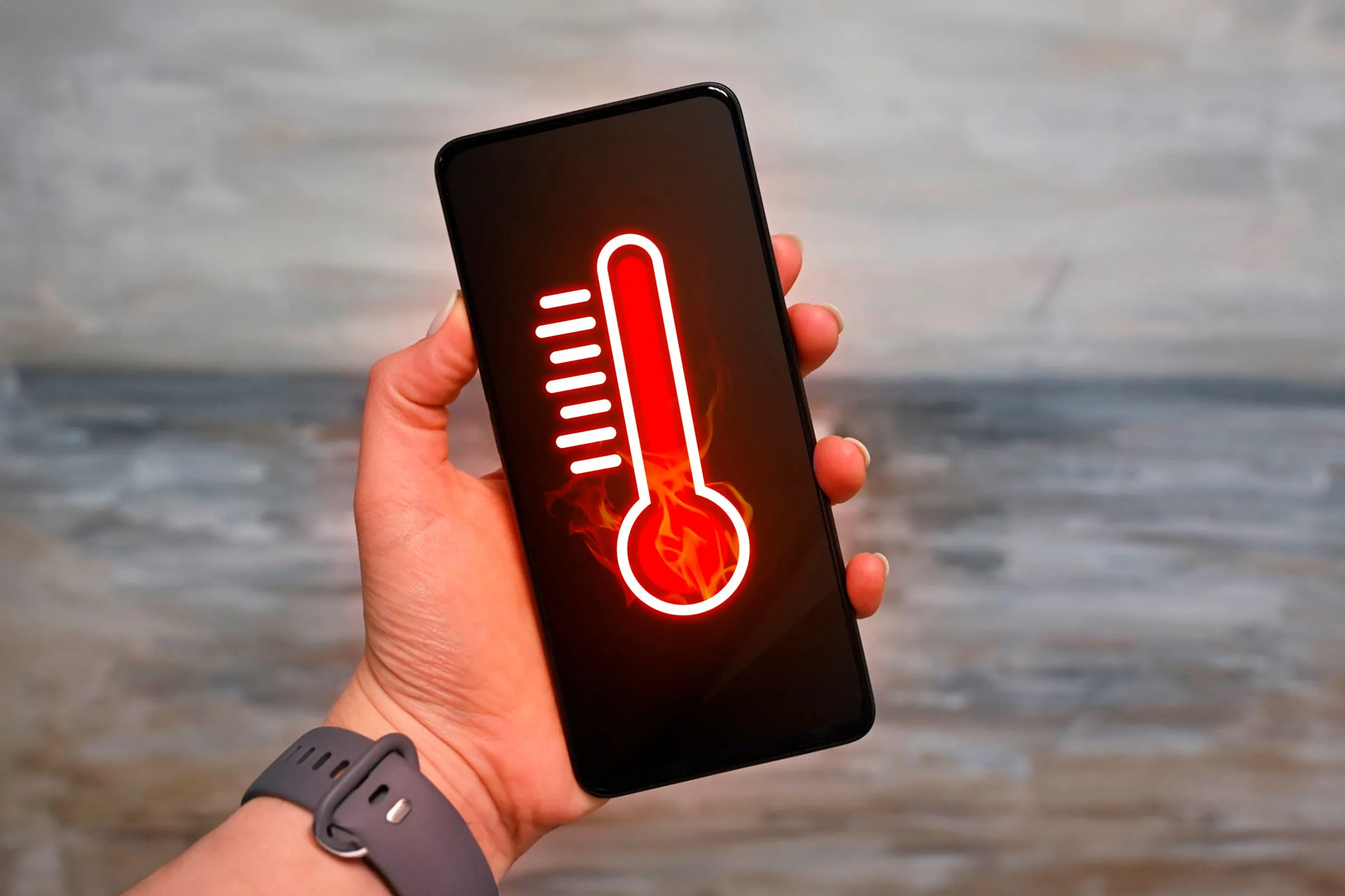 Bàn tay cầm smartphone với biểu tượng nhiệt kế, minh họa việc điện thoại bị nóng quá mức cần được làm mát
