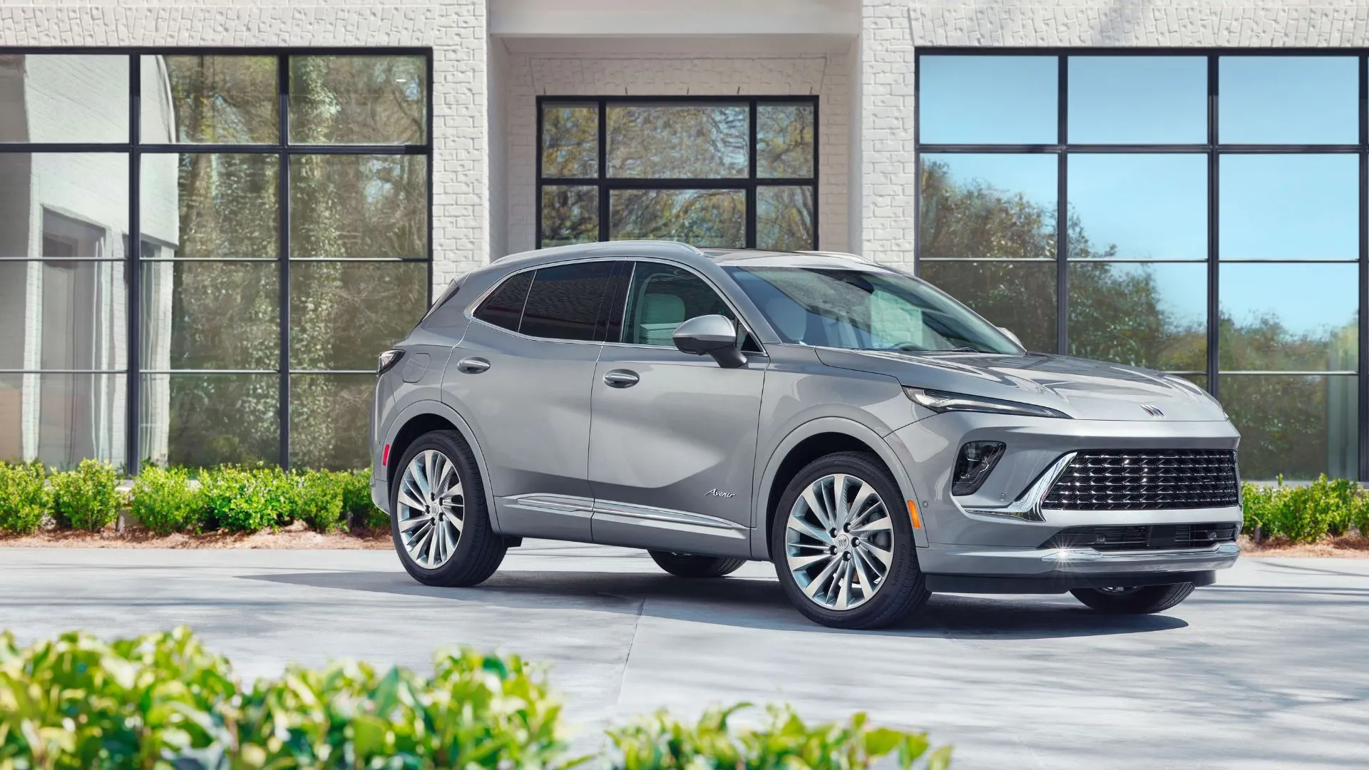 Buick Envision Avenir 2025 màu xám lịch lãm đậu bên ngoài tòa nhà kính, thể hiện nội thất cao cấp và công nghệ hiện đại