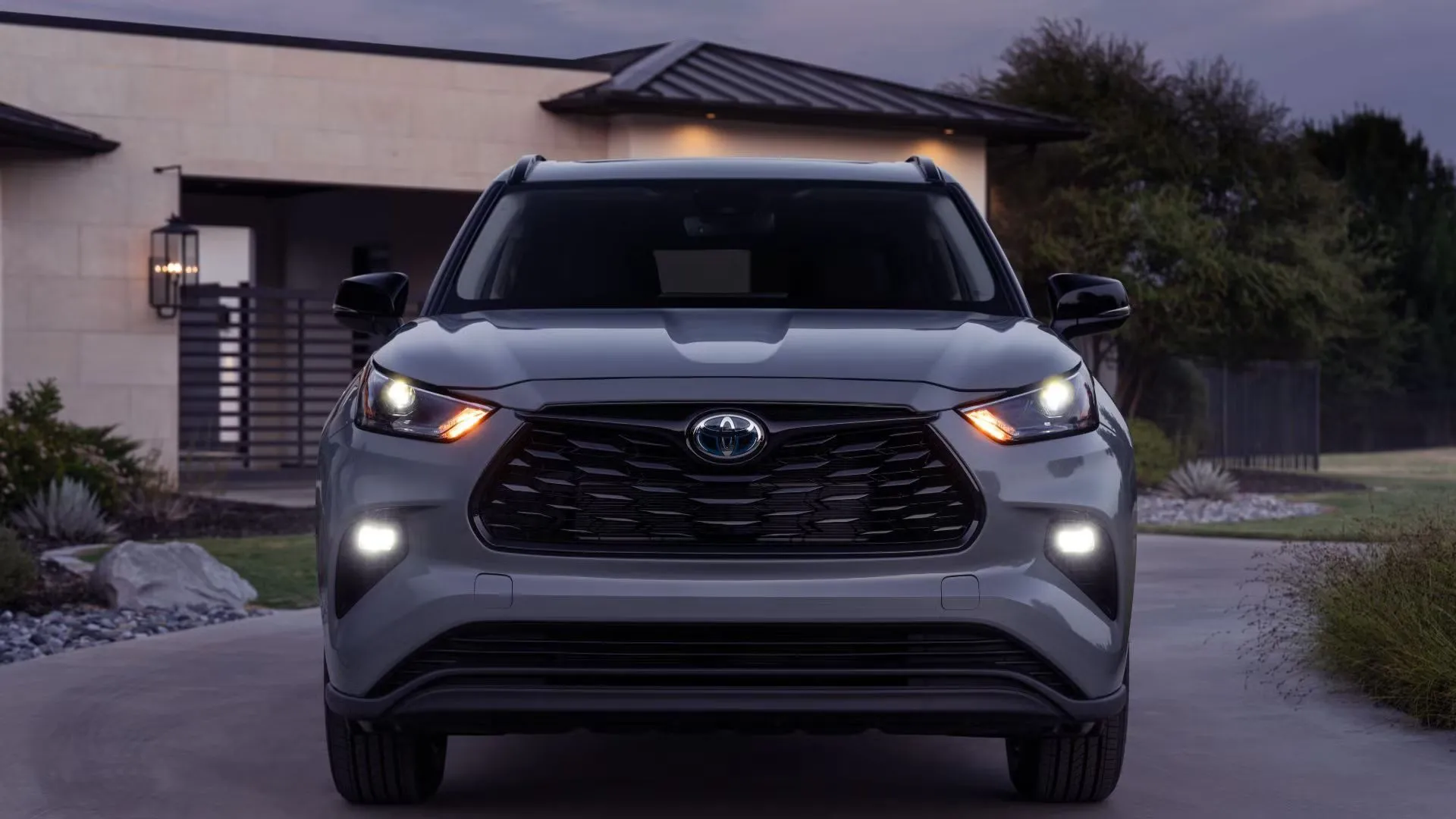 Cận cảnh phần đầu xe SUV Toyota Highlander 2024 màu xám đậm đậu trước nhà