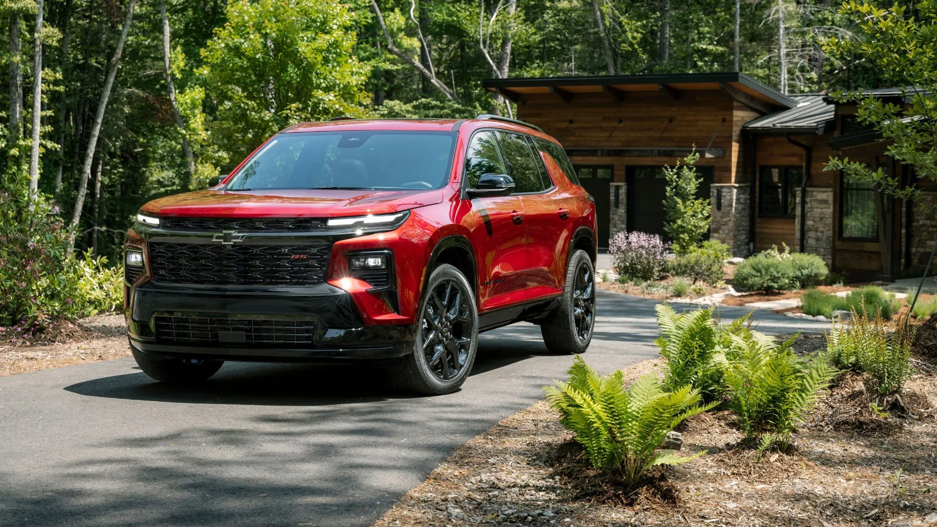 Chevrolet Traverse RS 2024 màu đỏ đỗ trên đường lái xe, mẫu SUV 3 hàng ghế cỡ trung đáng tin cậy của Chevrolet