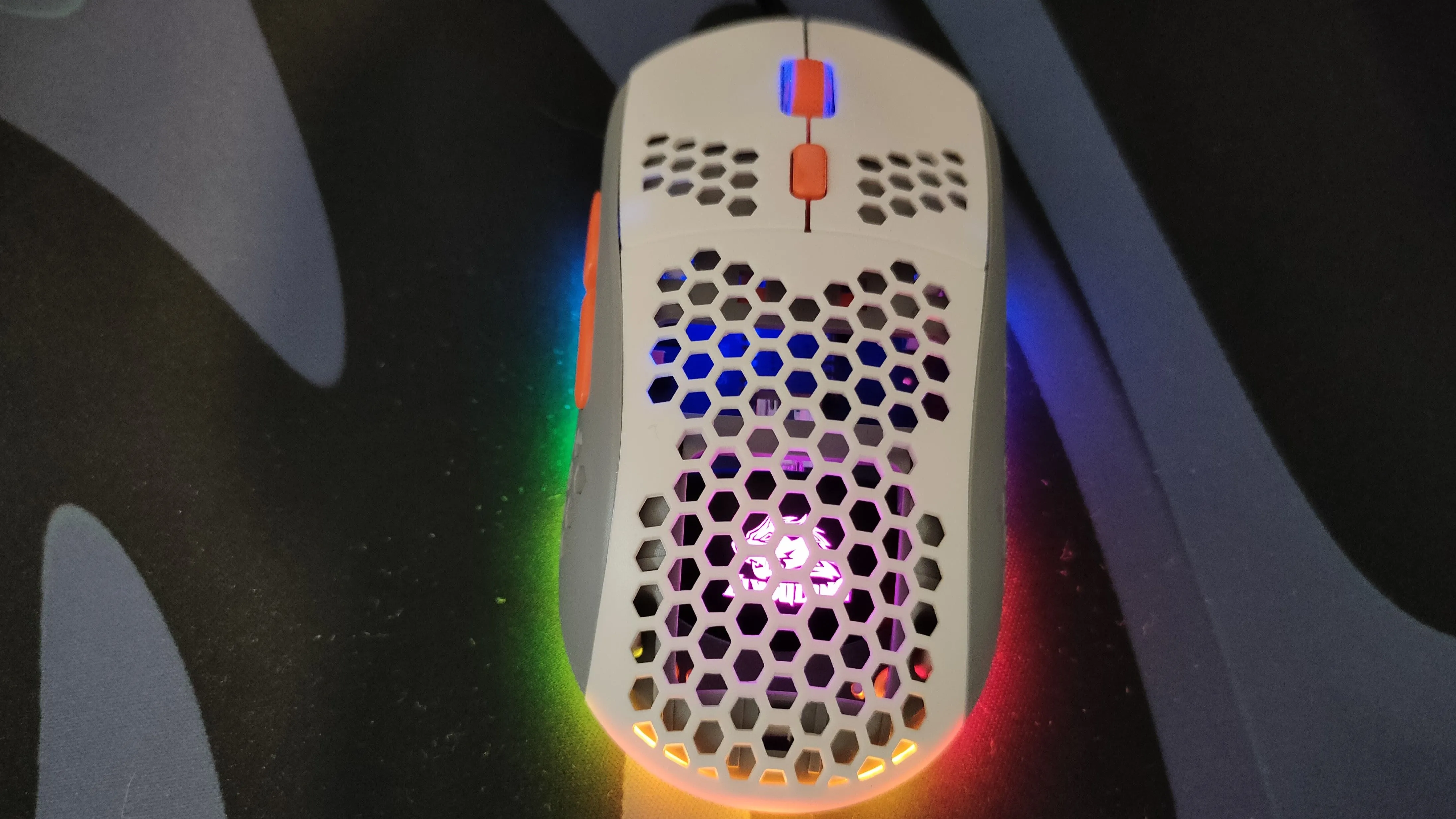 Chuột gaming màu trắng với thiết kế vỏ đục lỗ tổ ong và đèn RGB.
