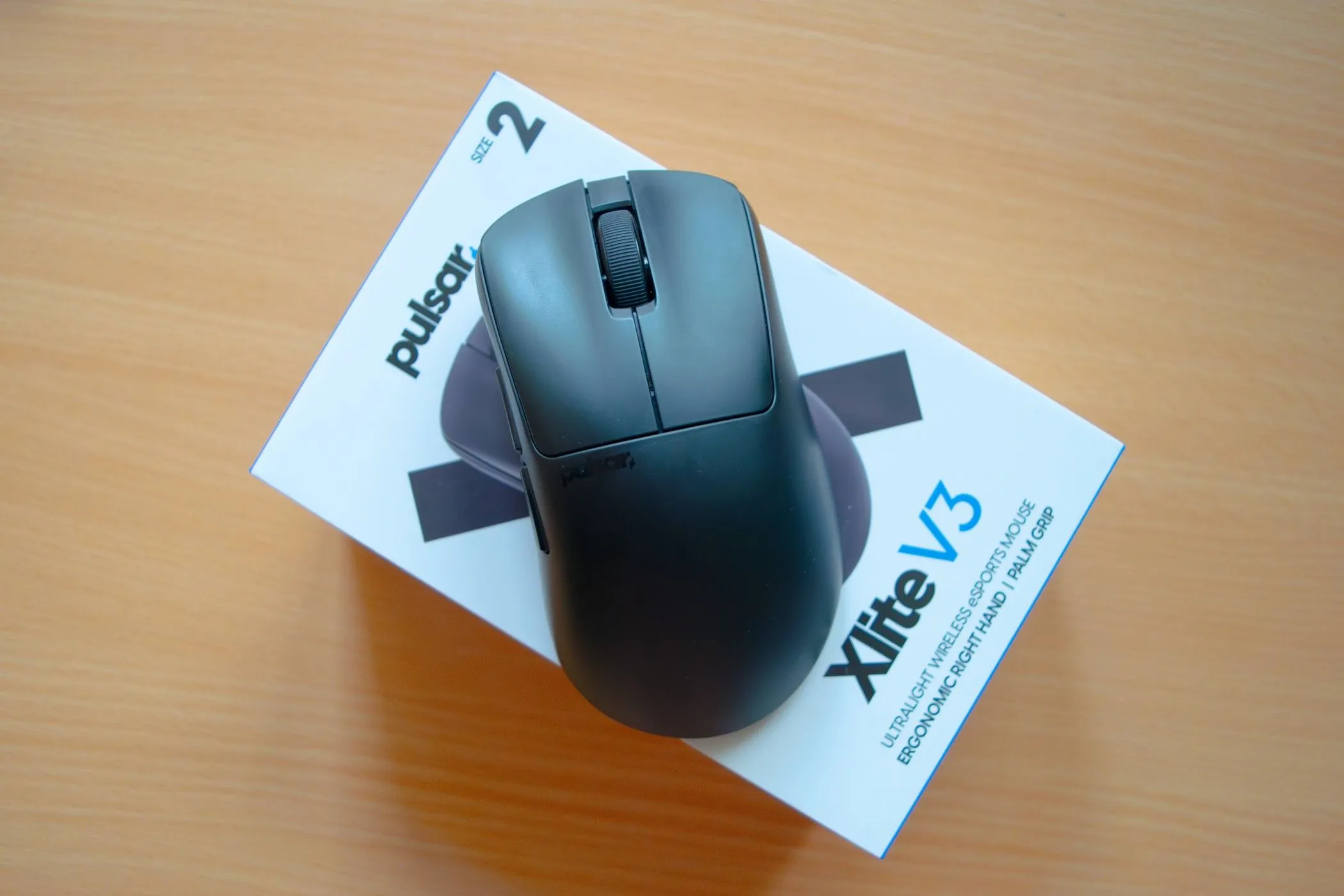 Chuột gaming siêu nhẹ Pulsar Xlite V3 màu trắng đặt trên hộp đựng của nó, nổi bật thiết kế tối giản.