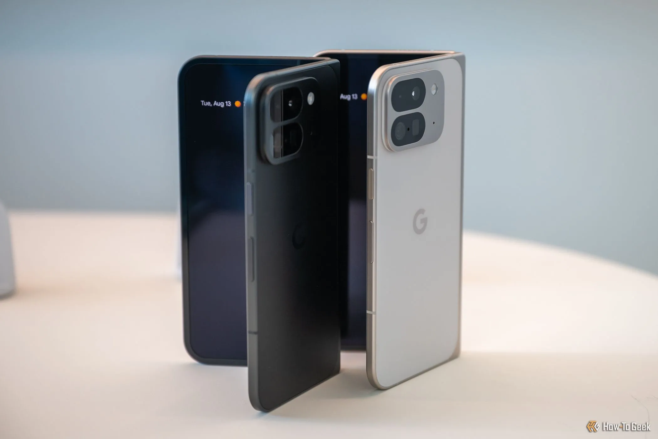 Điện thoại gập Google Pixel 9 Pro Fold màu sứ và đen obsidian mở nhẹ trên bàn