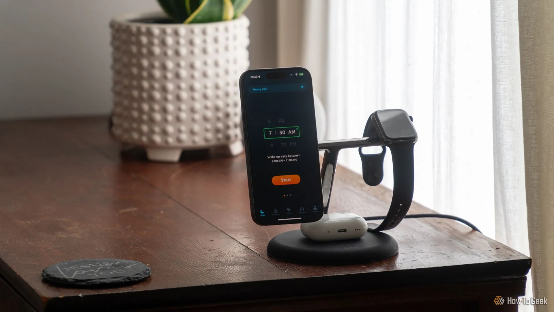 Điện thoại iPhone 15 Pro đang chạy ứng dụng Sleep Cycle trên bàn cạnh giường ngủ với Apple Watch và AirPods Pro