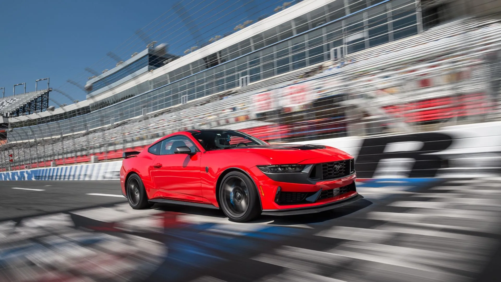 Ford Mustang Dark Horse 2025 màu đỏ đang chạy trên đường đua, thể hiện hiệu suất mạnh mẽ