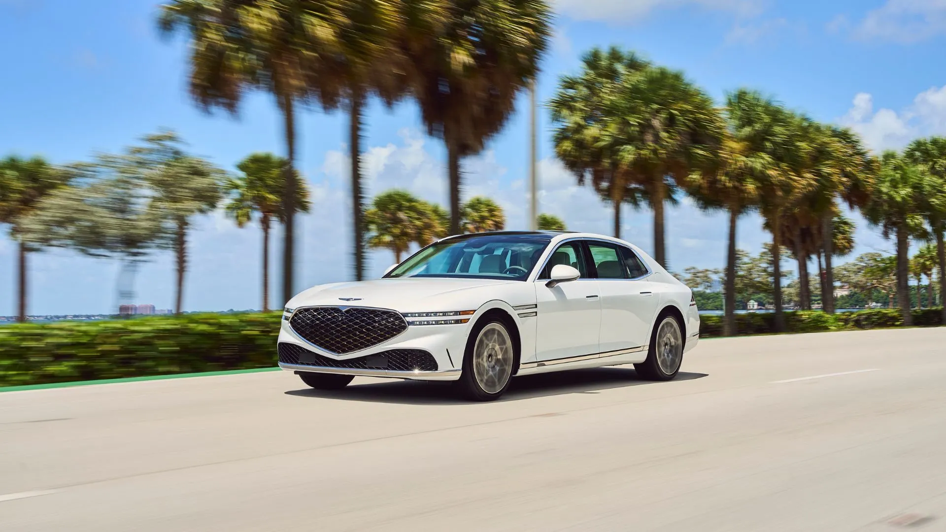 Genesis G90 2025 màu trắng di chuyển trên đường cao tốc, sử dụng công nghệ Highway Driving Assist II.