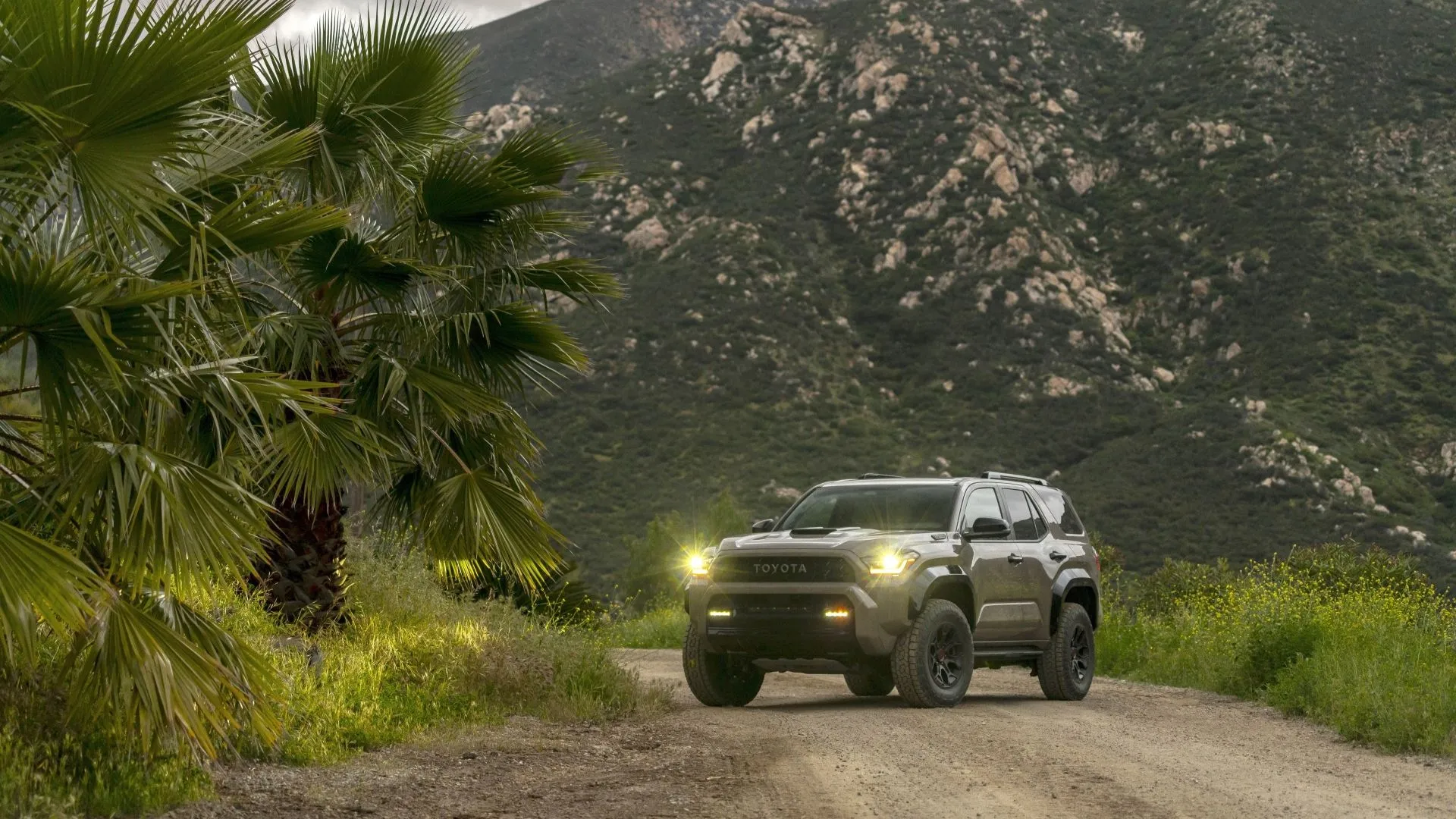 Góc 3/4 phía trước của chiếc SUV Toyota 4Runner TRD Pro 2025 màu vàng cam đang lội bùn