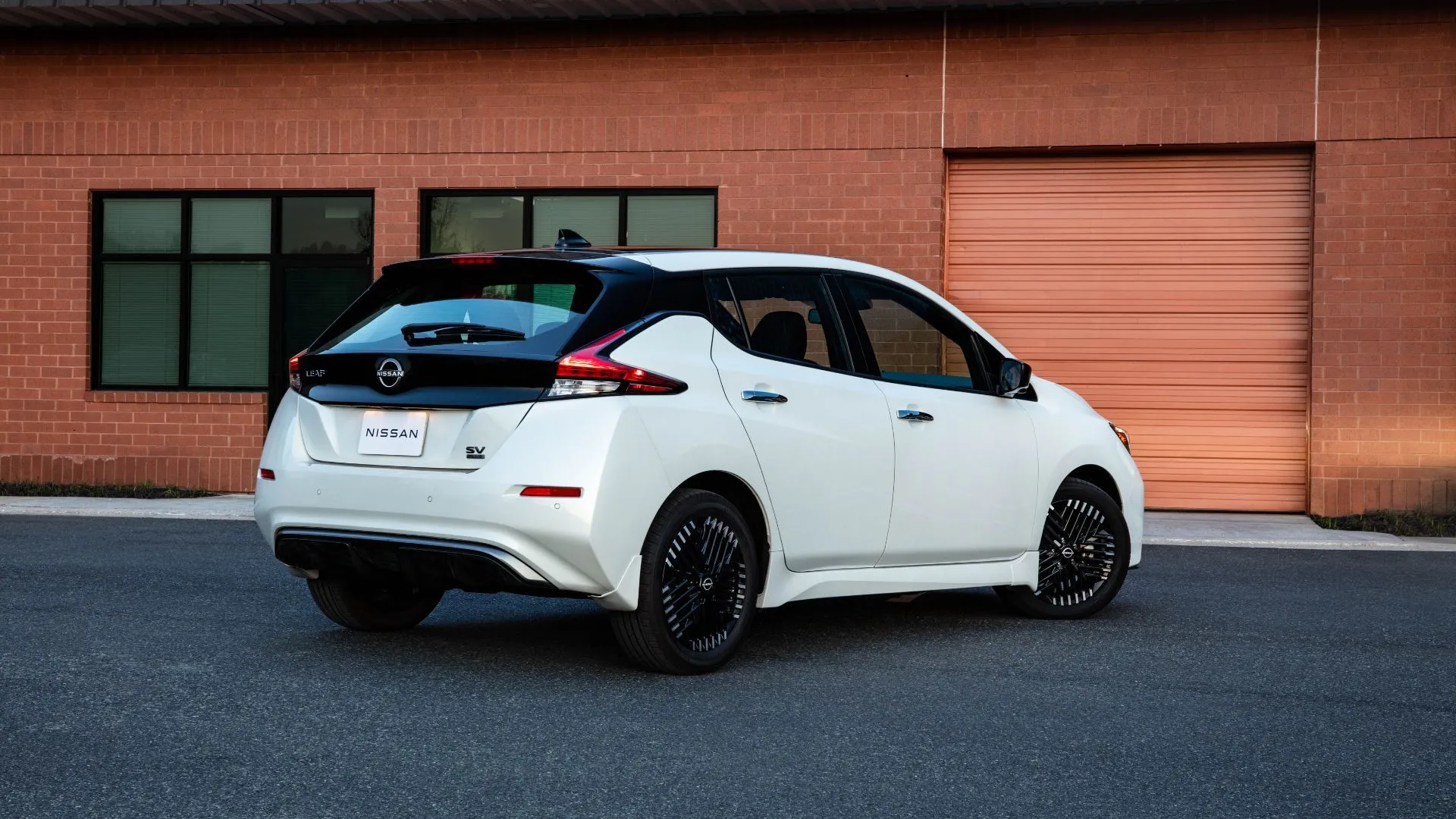 Góc nhìn phía sau của Nissan Leaf 2025 màu trắng đỗ trên đường