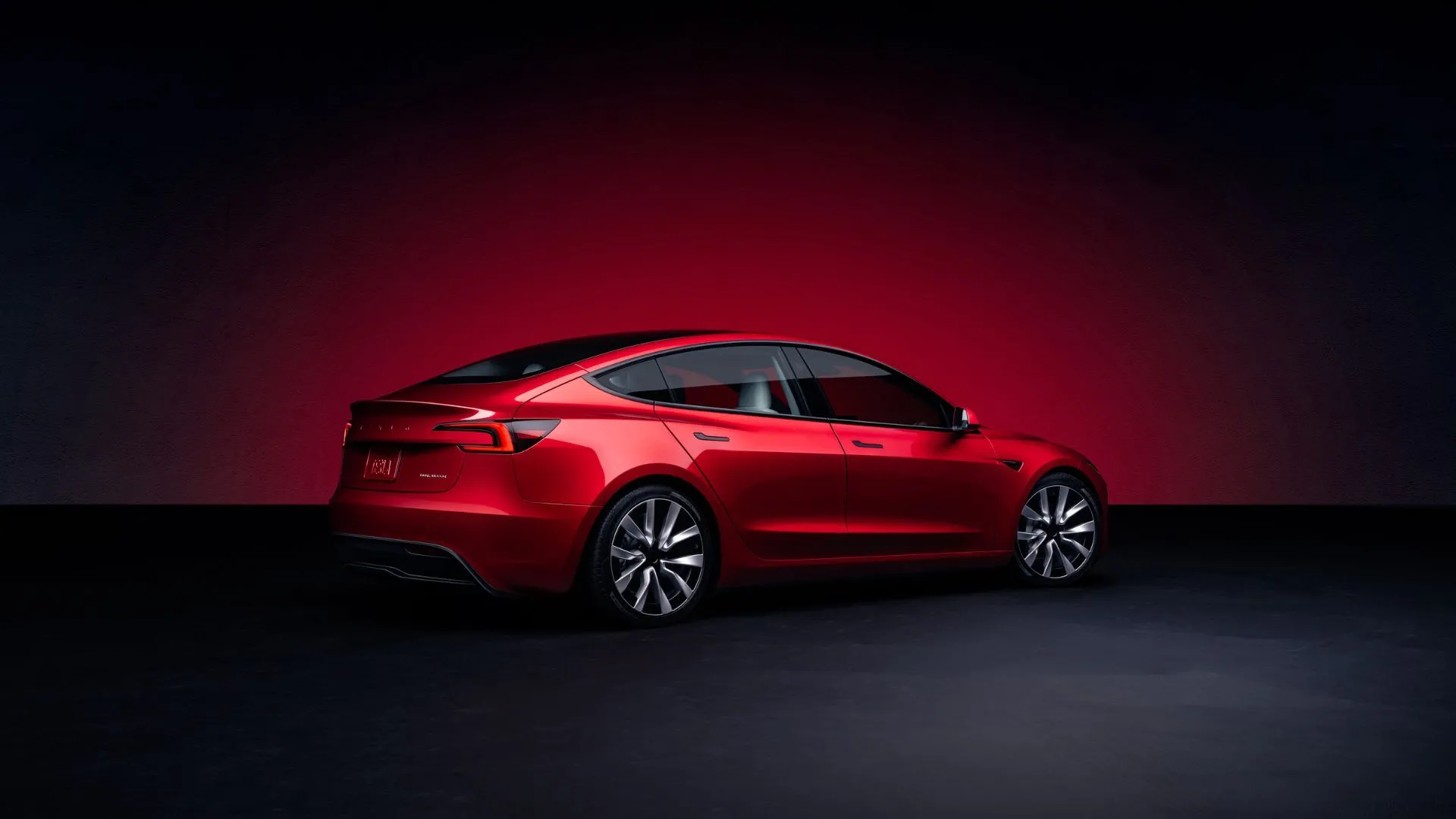 Góc nhìn phía sau của Tesla Model 3 màu đỏ trong studio, đèn hậu LED