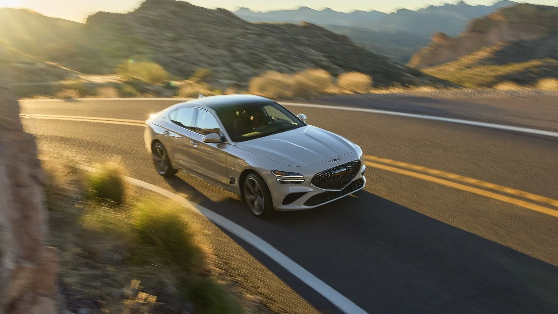 Hình ảnh chiếc Genesis G70 2025 màu xám bạc đang di chuyển, mẫu sedan sang trọng với chi phí bảo dưỡng hợp lý.