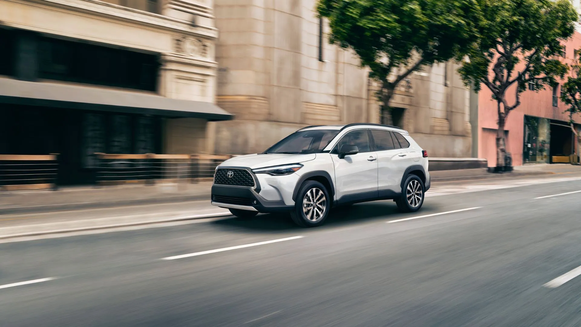 Hình ảnh chiếc Toyota Corolla Cross Hybrid XSE 2025 màu trắng ngọc trai đang di chuyển trên đường phố đông đúc