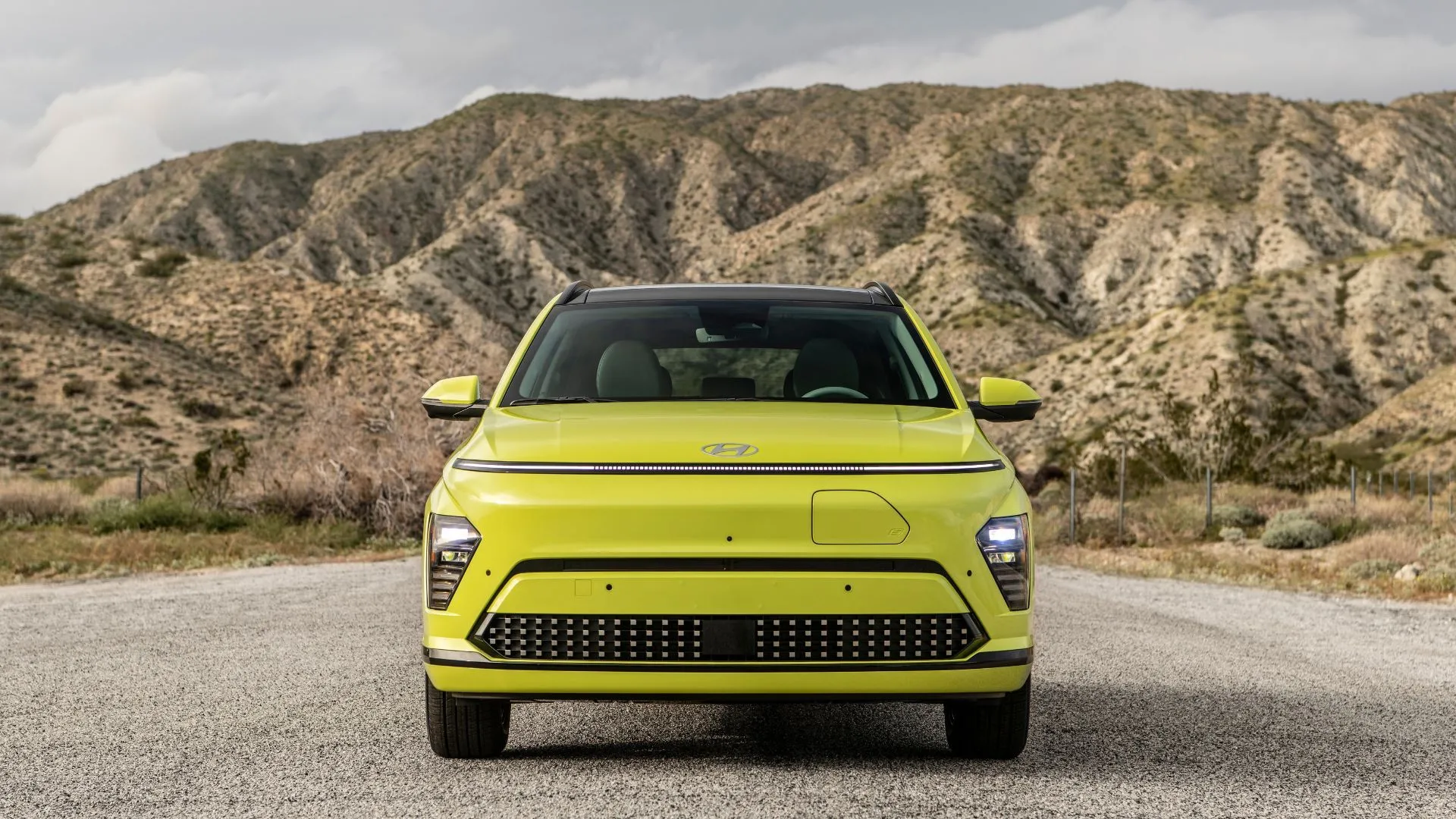 Hình ảnh Hyundai Kona Electric 2025 màu vàng đậu trước núi non hùng vĩ