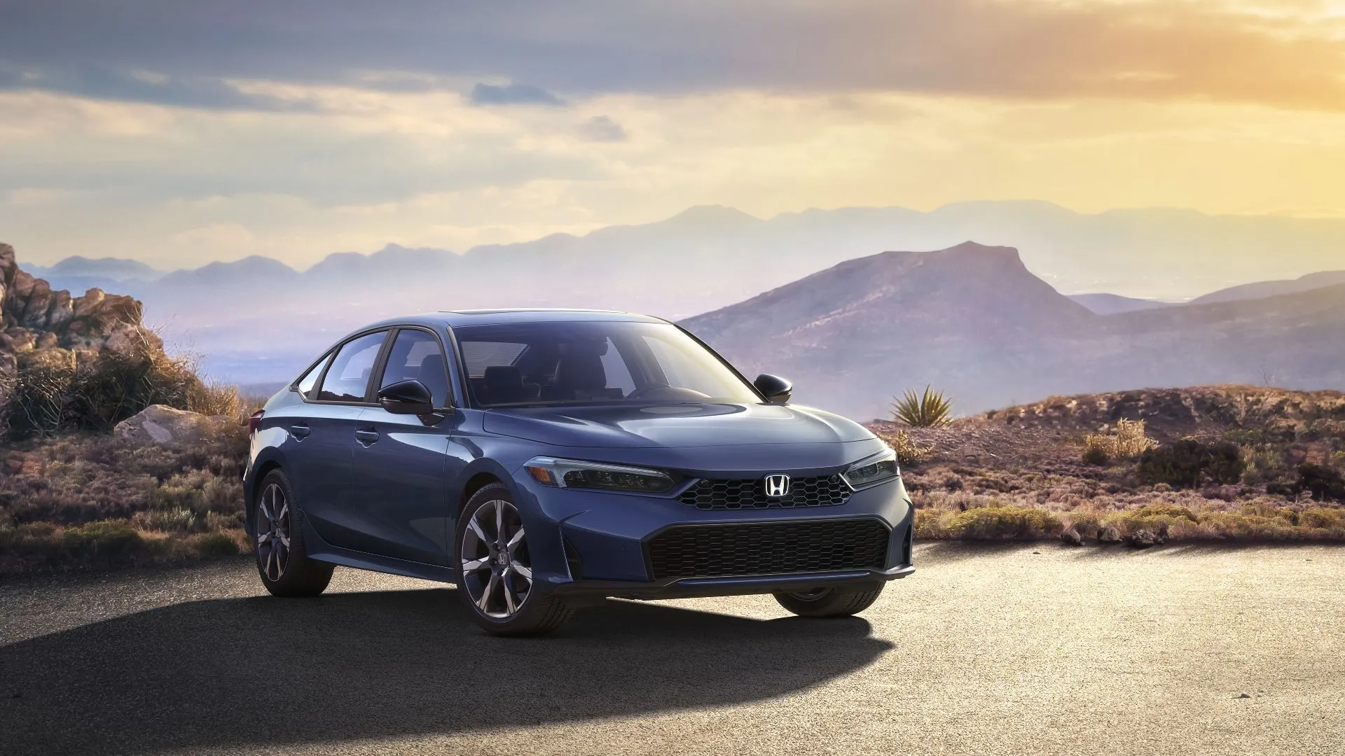 Honda Civic Sedan Sport Touring Hybrid 2025 đỗ trên đường nhựa với núi làm nền