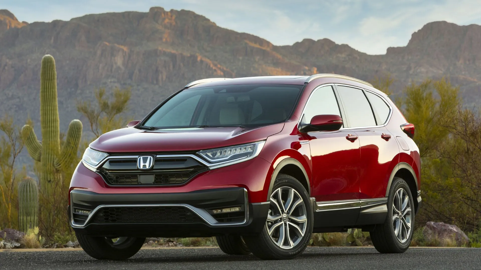 Honda CR-V Hybrid 2020 màu đỏ đỗ trên đường nhựa với xương rồng và núi phía sau, thể hiện sự cân bằng giữa hiệu suất và tiện nghi.