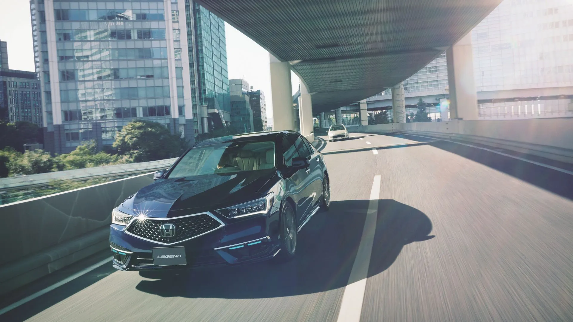Honda Legend 2021 màu xanh đang di chuyển dưới cầu trong thành phố.