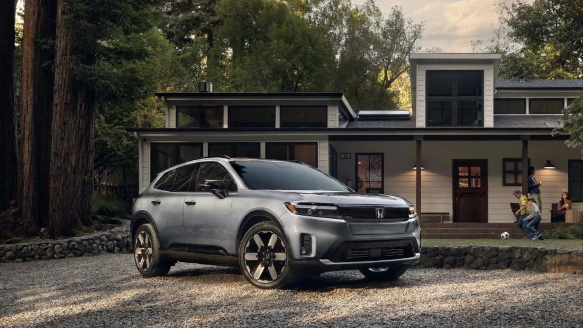Honda Prologue EV màu bạc đỗ trước nhà, thể hiện thiết kế hiện đại và thân thiện với gia đình