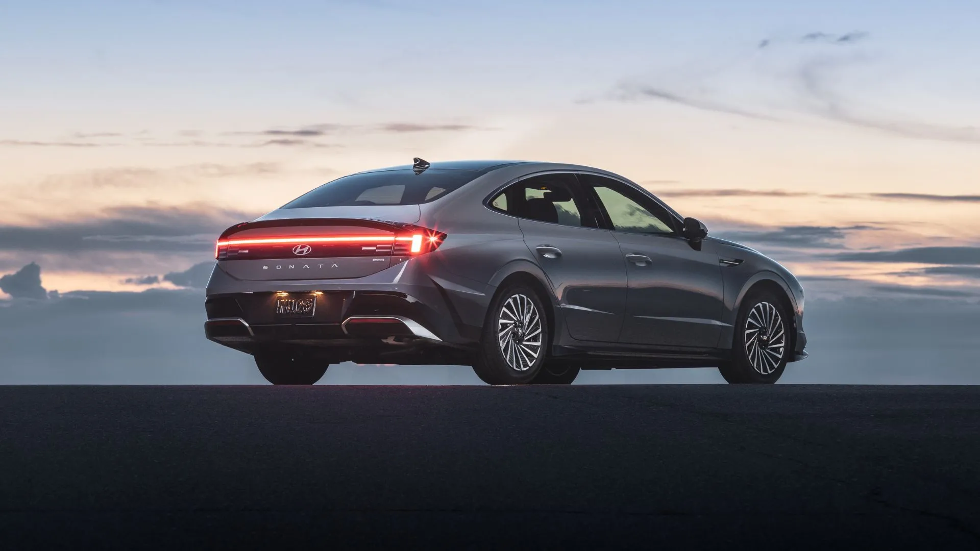 Hyundai Sonata Hybrid Limited 2025 màu xám từ góc phía sau vào lúc hoàng hôn, tôn lên thiết kế đuôi xe thanh lịch
