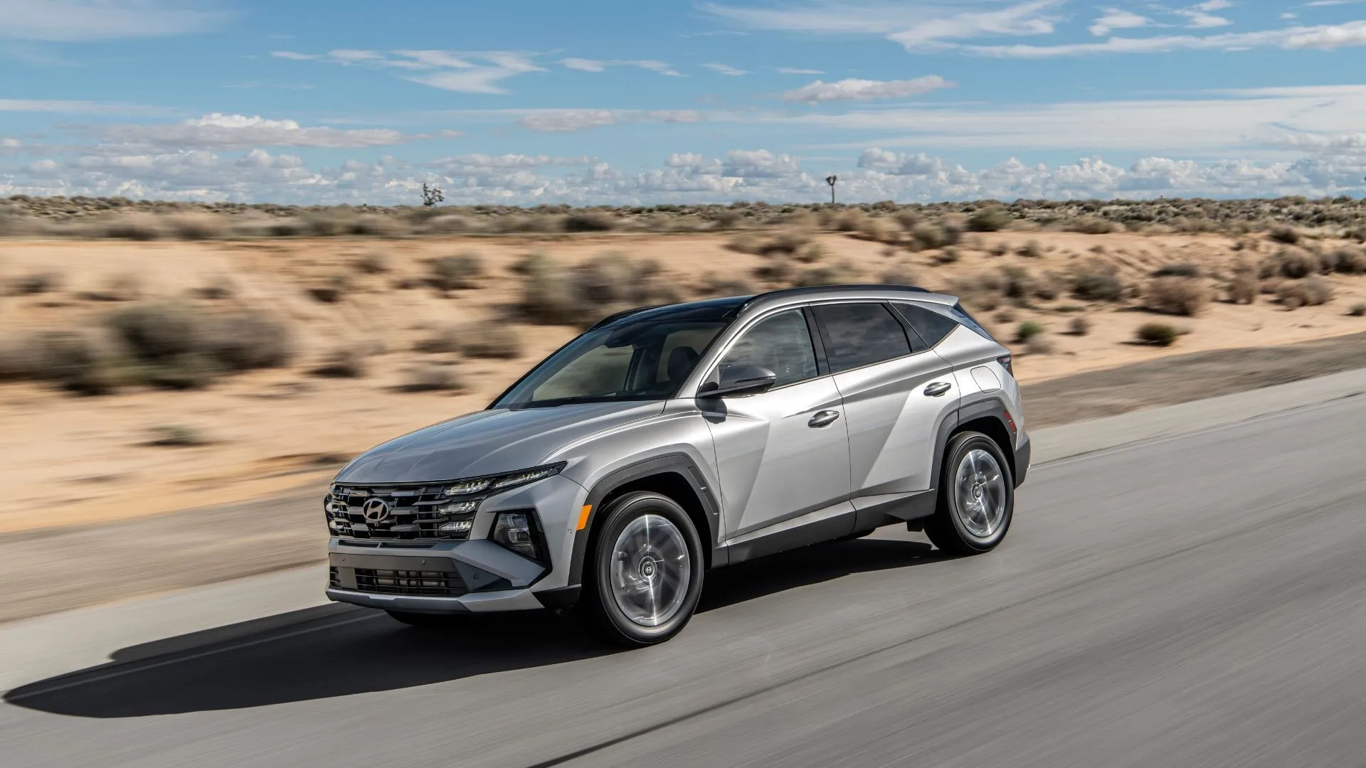 Hyundai Tucson PHEV 2025 màu xám di chuyển trên đường sa mạc, mẫu SUV plug-in hybrid