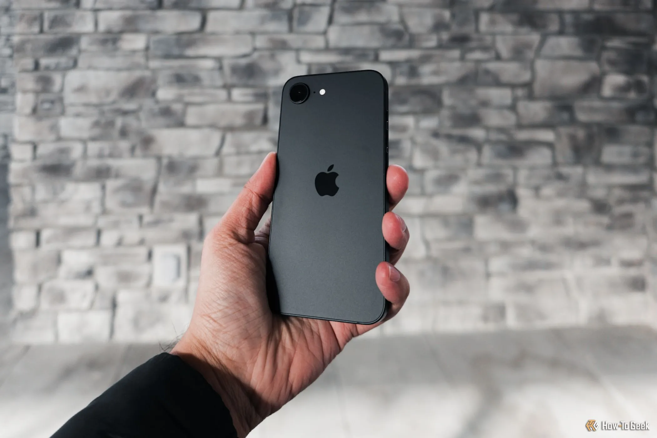 iPhone 16e màu trắng được cầm nghiêng nhẹ trên tay