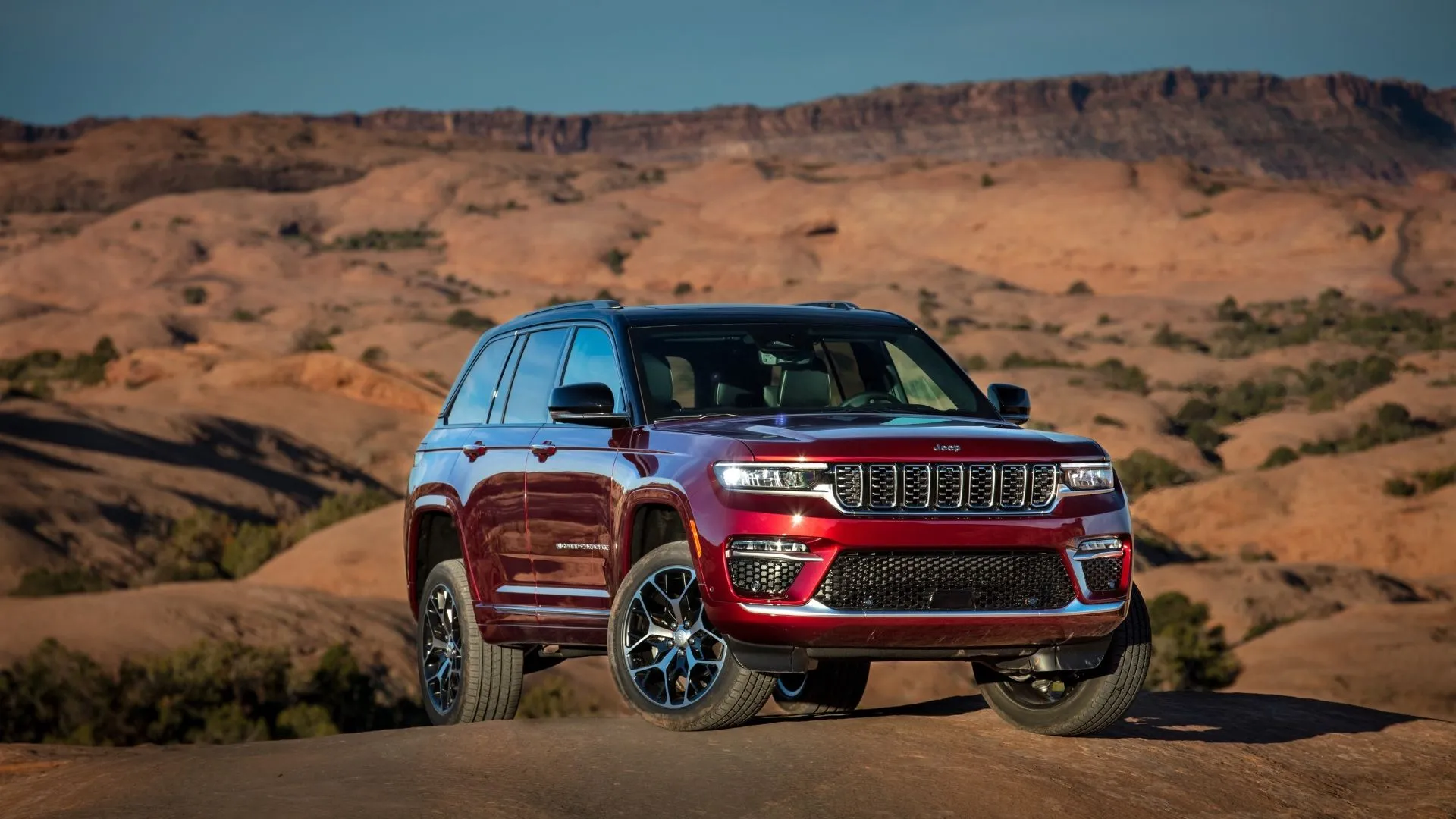Jeep Grand Cherokee 2025 màu trắng ngà đứng vững trên nền đồi núi, thể hiện sự sang trọng và khả năng vượt địa hình của dòng SUV tầm trung
