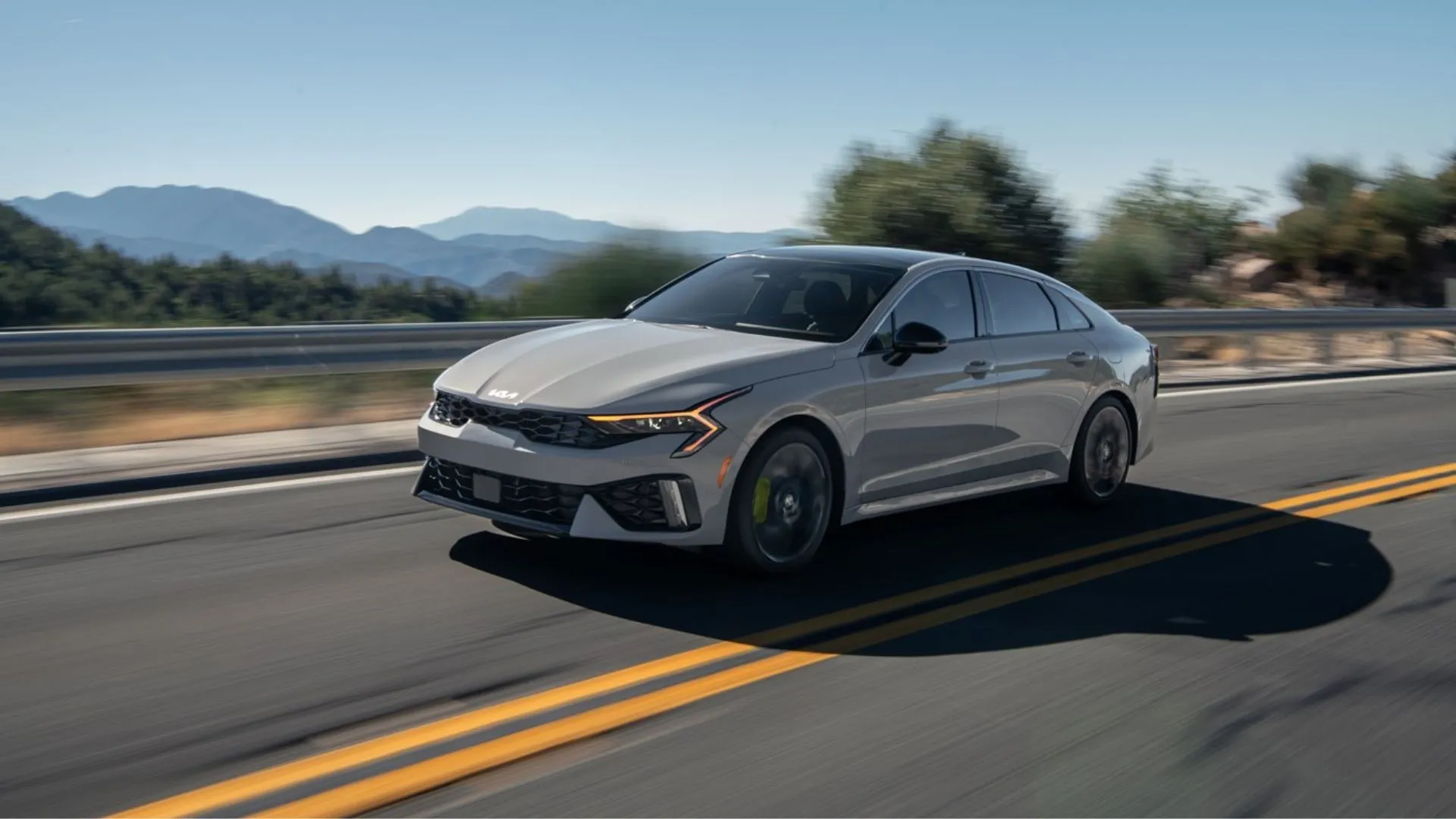 Kia K5 2025 màu xám bạc đang chạy trên đường núi