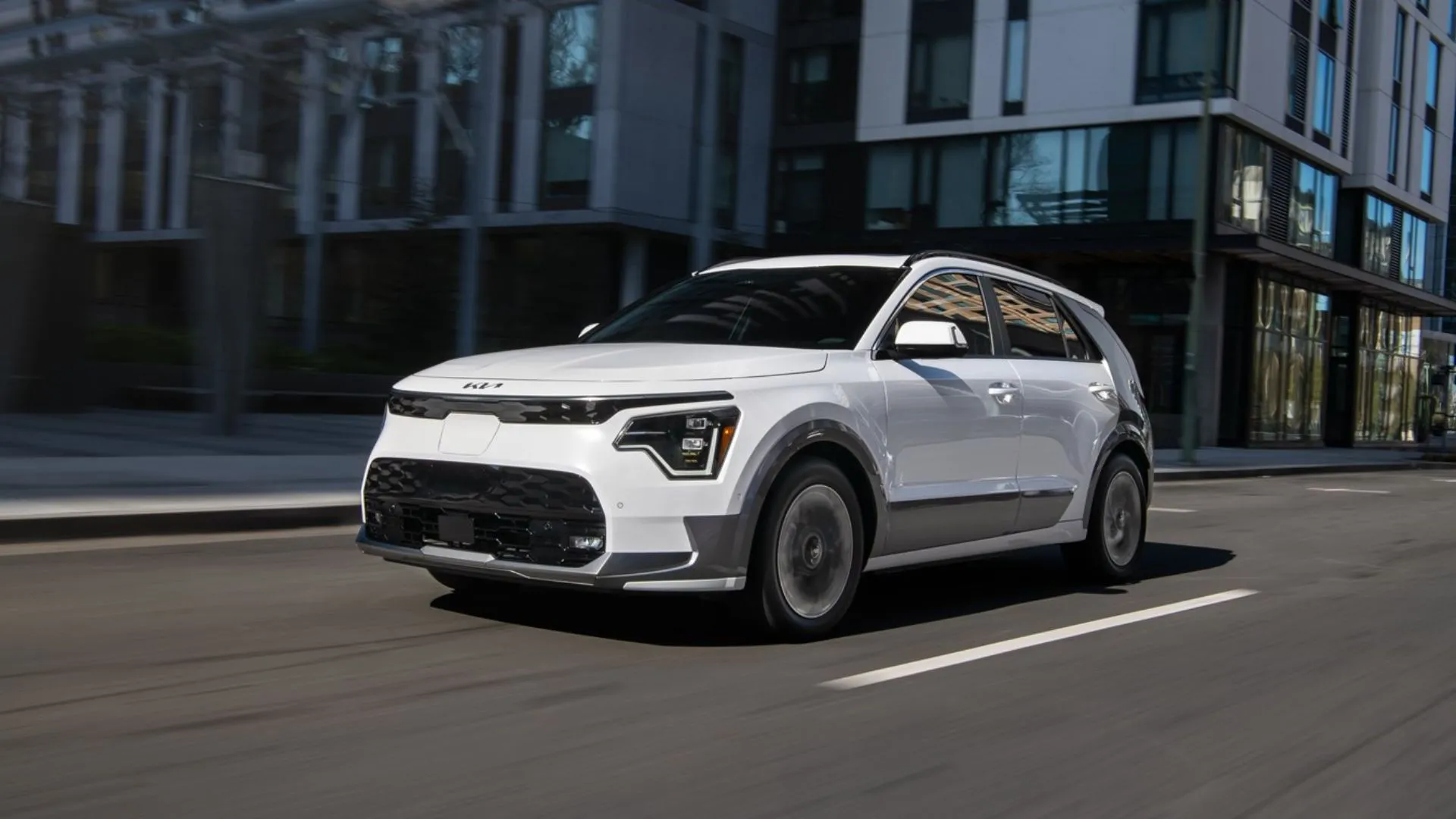 KIA Niro EV 2025 màu trắng đang lái qua thành phố, góc nhìn ba phần tư phía trước.