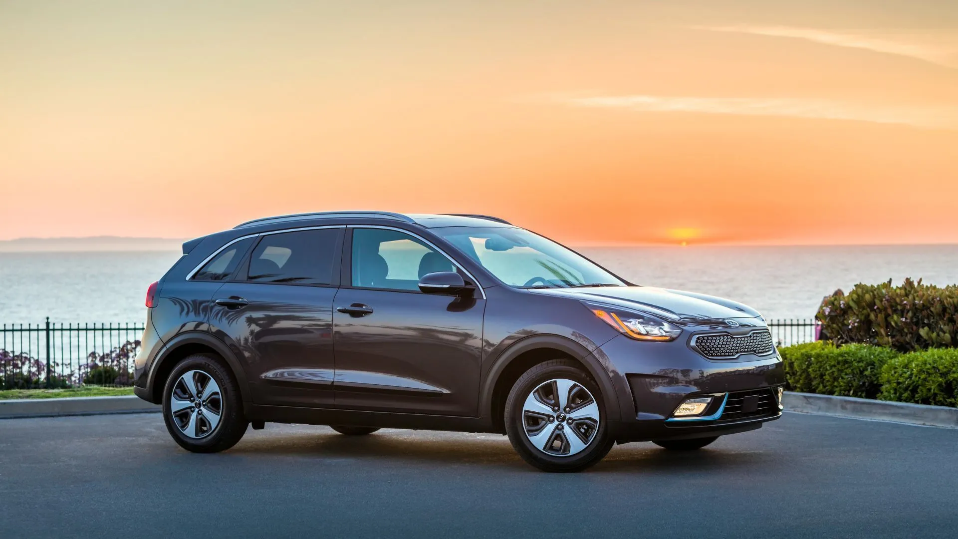 Kia Niro Plug-In Hybrid 2018 màu xám đỗ trên đường nhựa lúc hoàng hôn, thể hiện sự ưu việt về hiệu quả nhiên liệu và thiết kế nhỏ gọn.