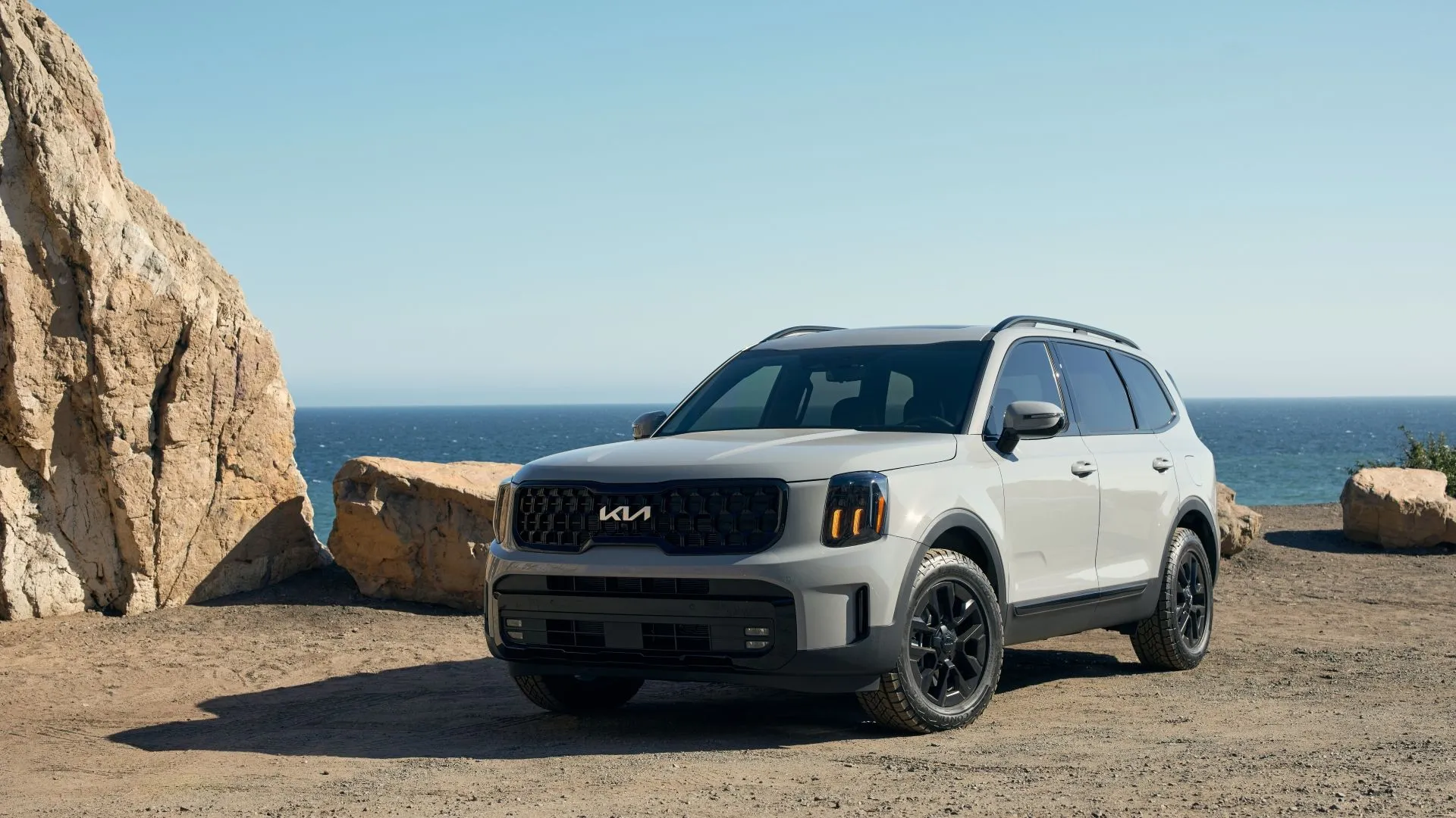 Kia Telluride 2025 màu trắng ngà mạnh mẽ và sang trọng, đứng yên trên nền trời xanh, thể hiện thiết kế góc cạnh của SUV tầm trung