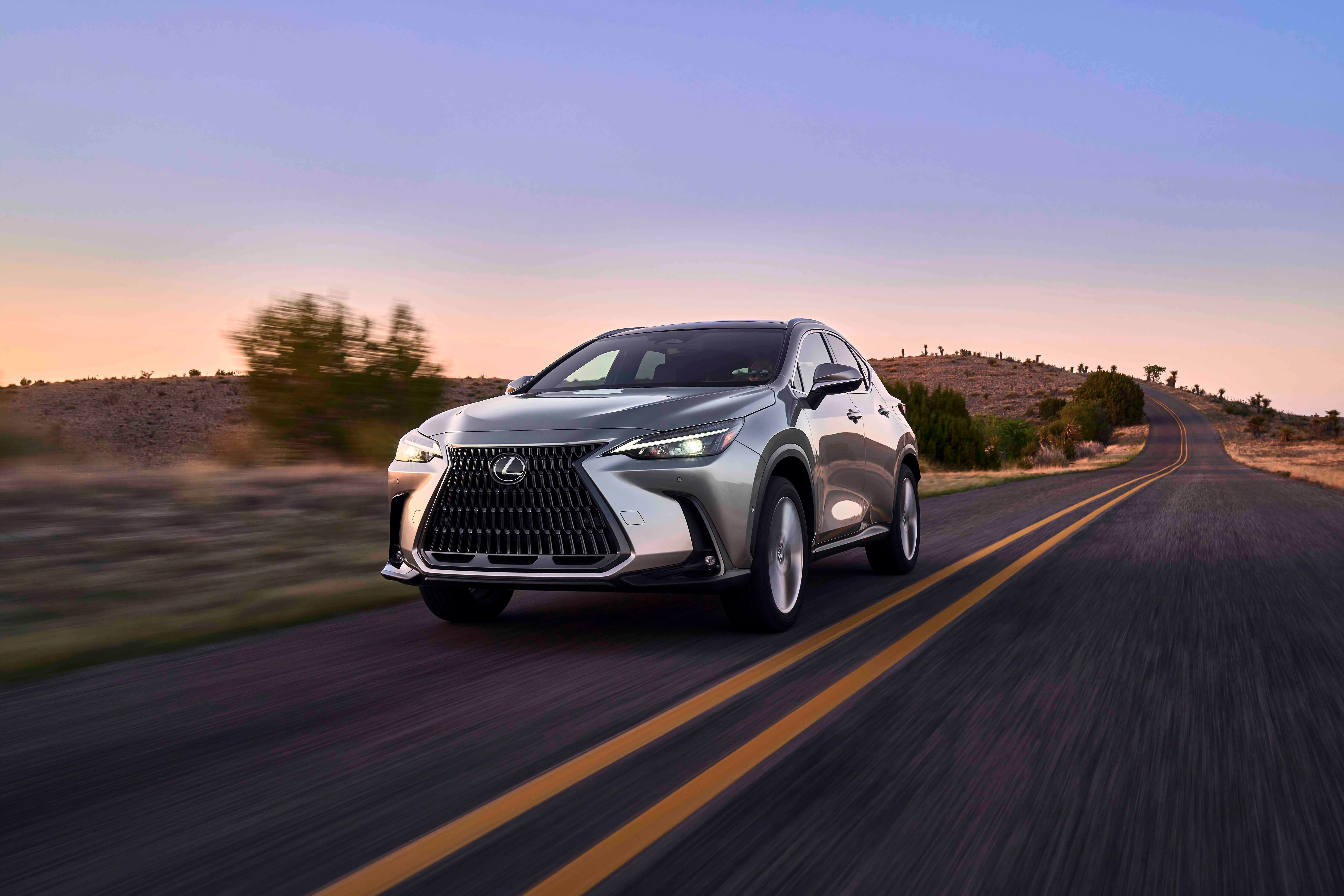 Lexus NX 350h 2024 màu bạc đang di chuyển trên đường quê, một mẫu SUV hybrid hạng sang hàng đầu với nội thất cao cấp và độ tin cậy vượt trội.